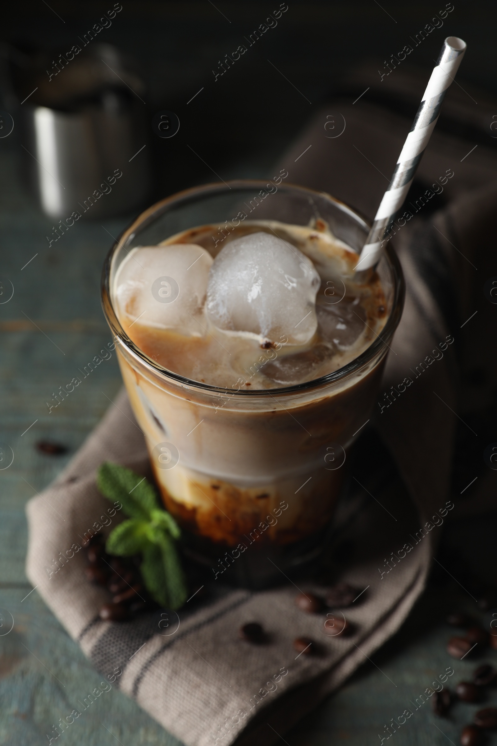 Photo of Glass of delicious iced coffee, beans and mint on table