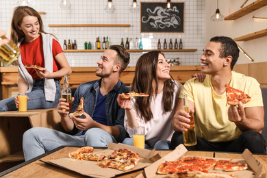 Photo of Group of friends having fun party with delicious pizza in cafe