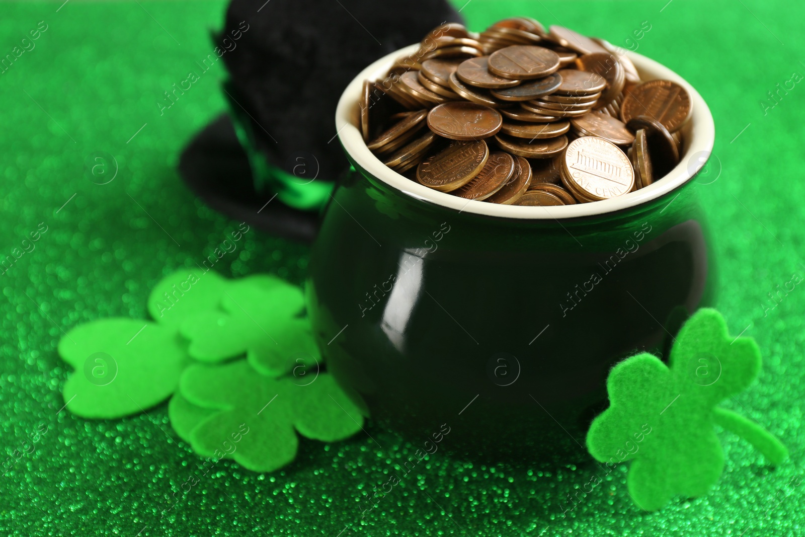 Photo of Pot of gold coins and clover leaves on green background, closeup. St. Patrick's Day celebration