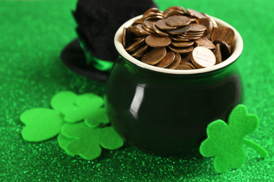 Photo of Pot of gold coins and clover leaves on green background, closeup. St. Patrick's Day celebration