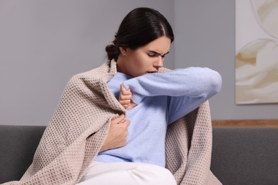 Photo of Woman coughing on sofa at home. Cold symptoms