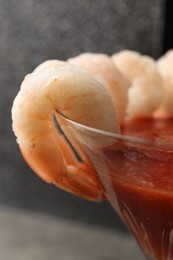 Tasty shrimp cocktail with sauce in glass on grey background, closeup