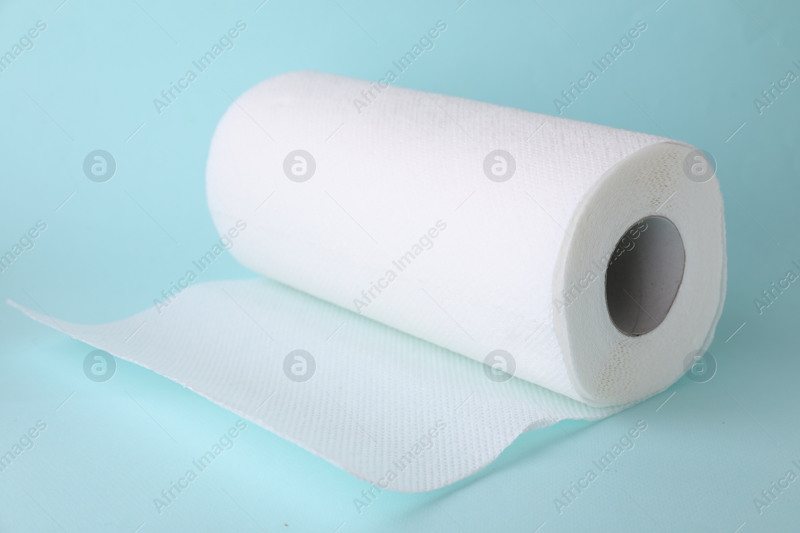 Photo of One roll of paper towels on light blue background, closeup