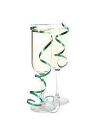 Photo of Glasses of champagne and serpentine streamers on white background
