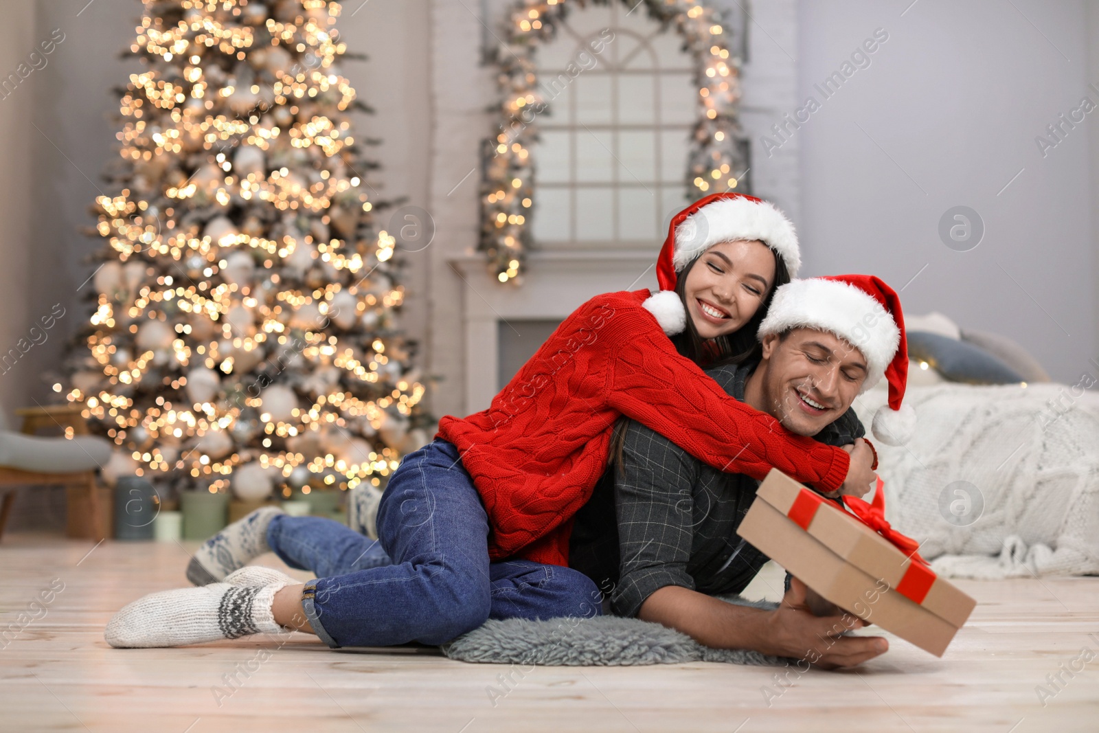 Photo of Young woman presenting Christmas gift to her boyfriend at home