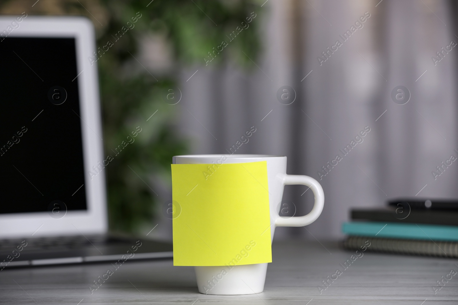 Photo of Cup with blank sticky note on white wooden table indoors. Space for text