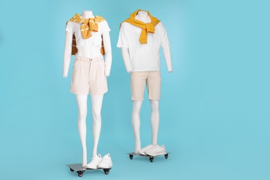 Photo of Mannequins with sneakers dressed in white t-shirts, shorts and orange sweaters on light blue background. Stylish male and female outfits