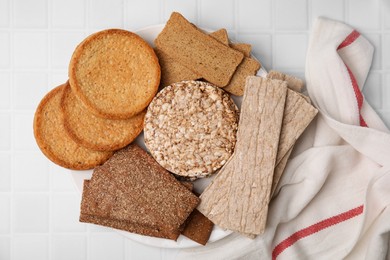 Photo of Rye crispbreads, rice cakes and rusks on white checkered table, flat lay