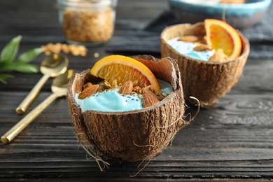 Photo of Coconut shells with yummy spirulina smoothie on wooden table