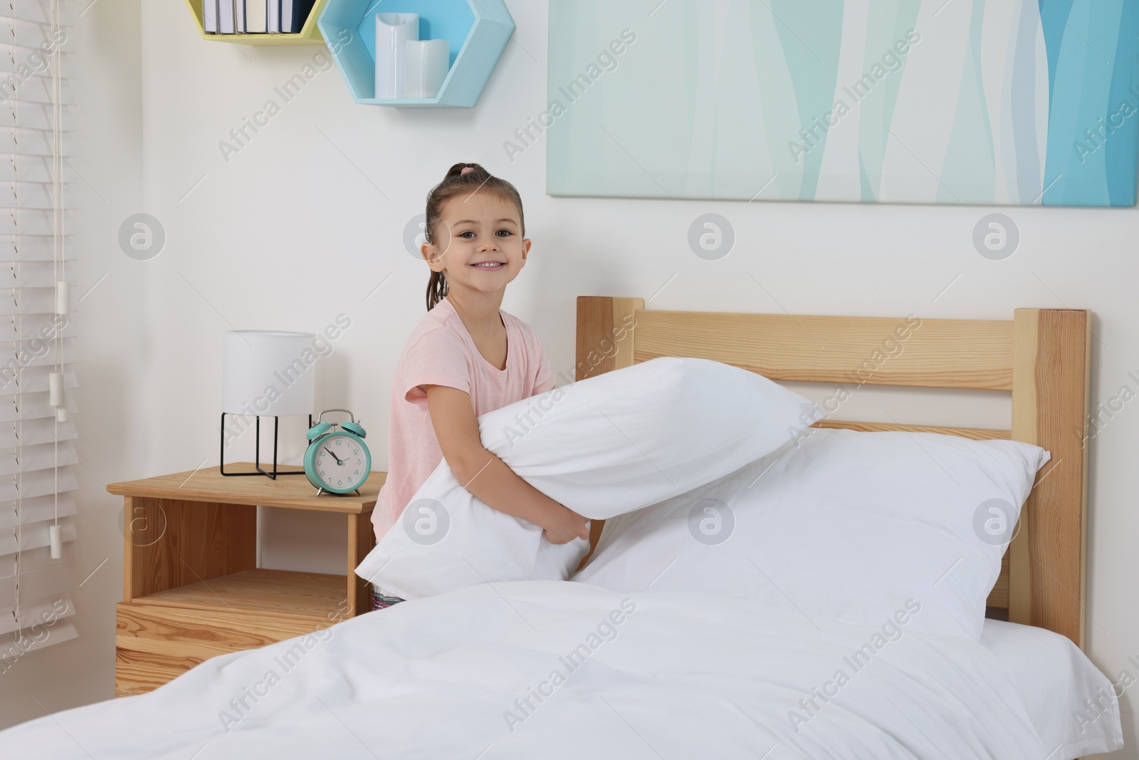 Photo of Cute girl changing bed linens in children room