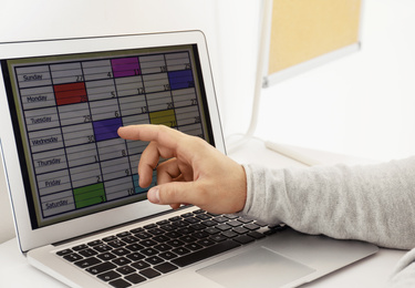 Young man using calendar app on laptop in office, closeup