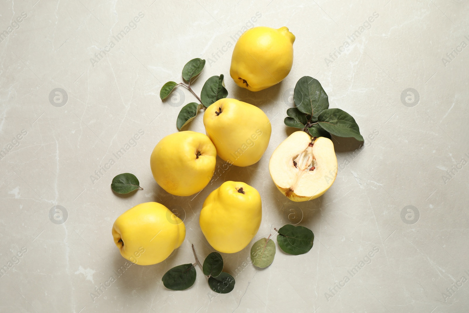 Photo of Fresh ripe organic quinces with leaves on light table, flat lay