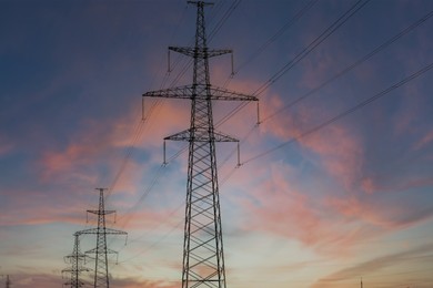 Photo of Telephone poles with cables at sunset outdoors