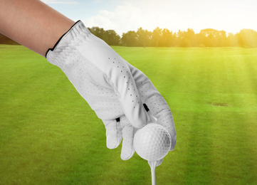 Image of Player putting golf ball on tee in park on sunny day, closeup