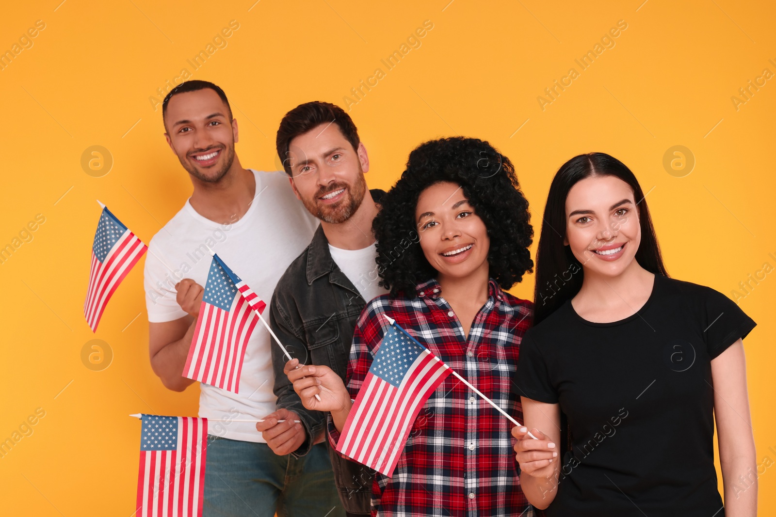 Photo of 4th of July - Independence Day of USA. Happy friends with American flags on yellow background