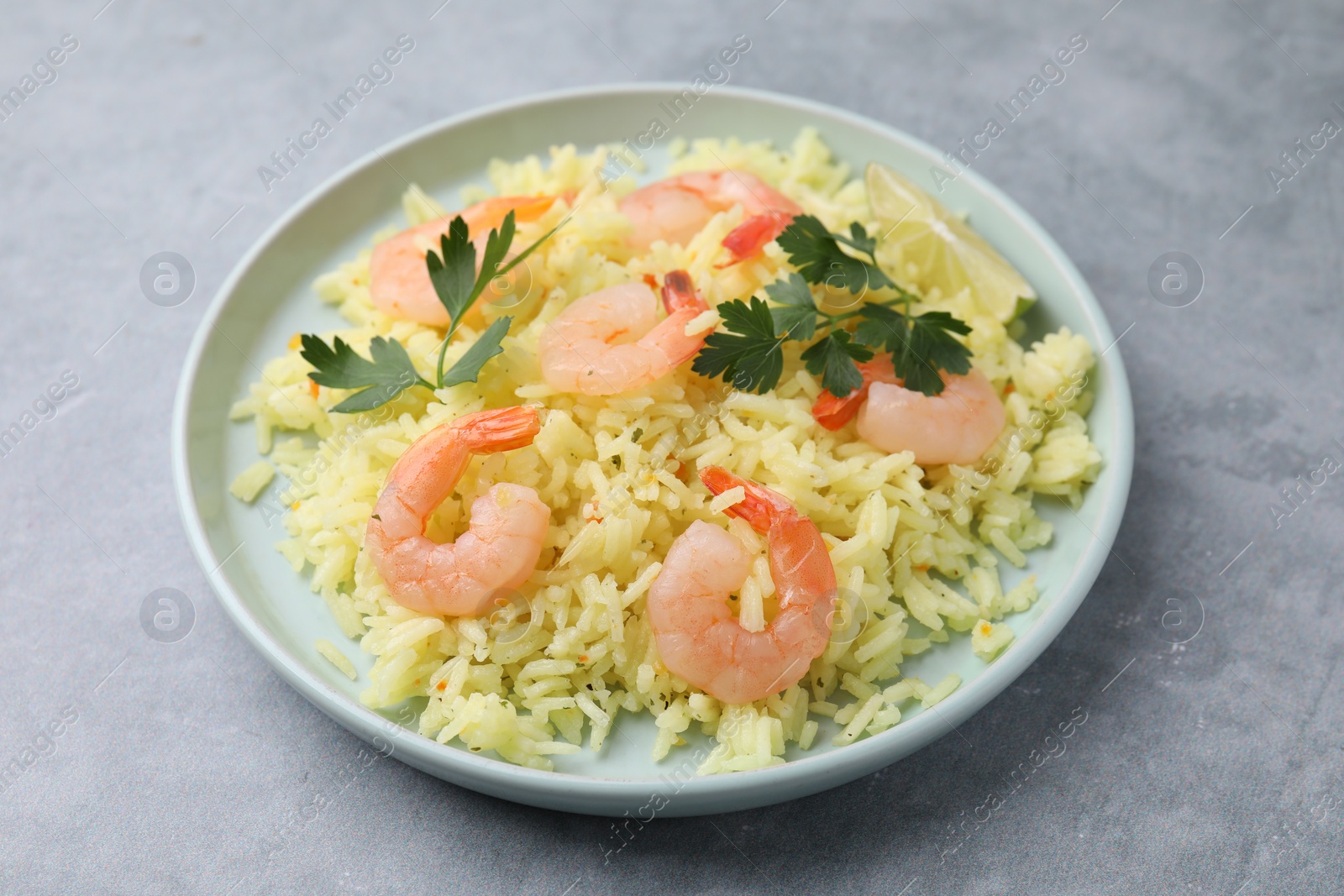 Photo of Delicious risotto with shrimps, lime and parsley on light grey table