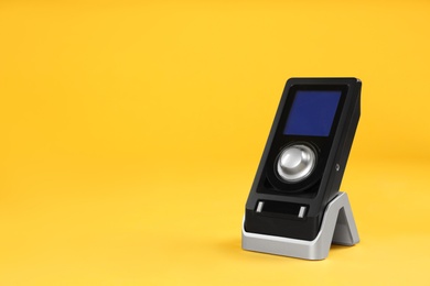 Photo of Modern remote for audio speakers on yellow background, space for text