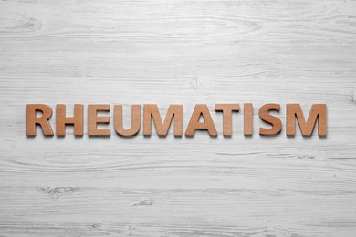 Photo of Word Rheumatism made of letters on white wooden table, top view
