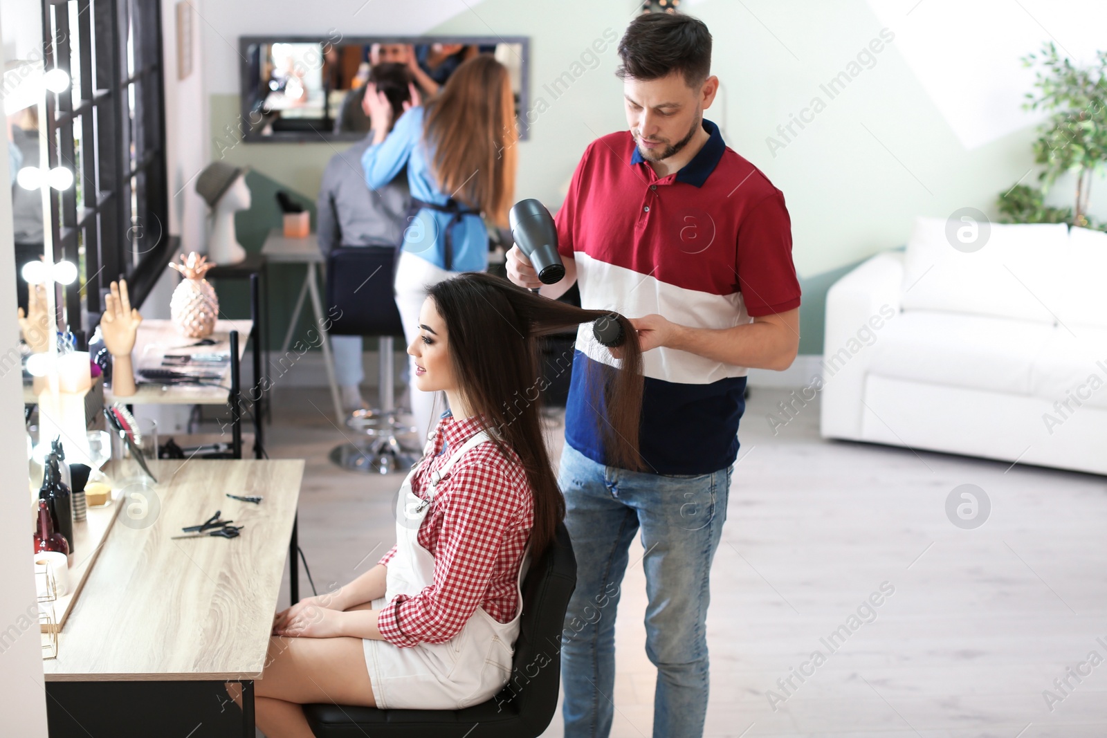 Photo of Professional hairdresser working with client in beauty salon