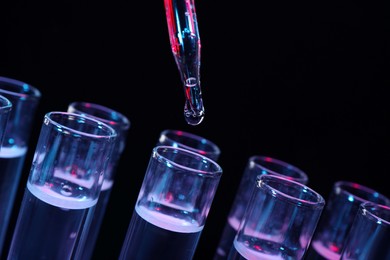 Photo of Dripping reagent into test tube on black background, closeup. Laboratory analysis