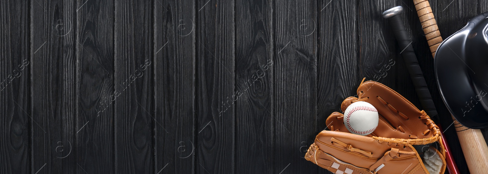 Image of Baseball glove, bats, ball and batting helmet on black wooden table, flat lay. Banner design with space for text