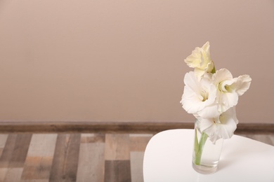 Photo of Vase with beautiful gladiolus flowers on wooden table indoors. Space for text