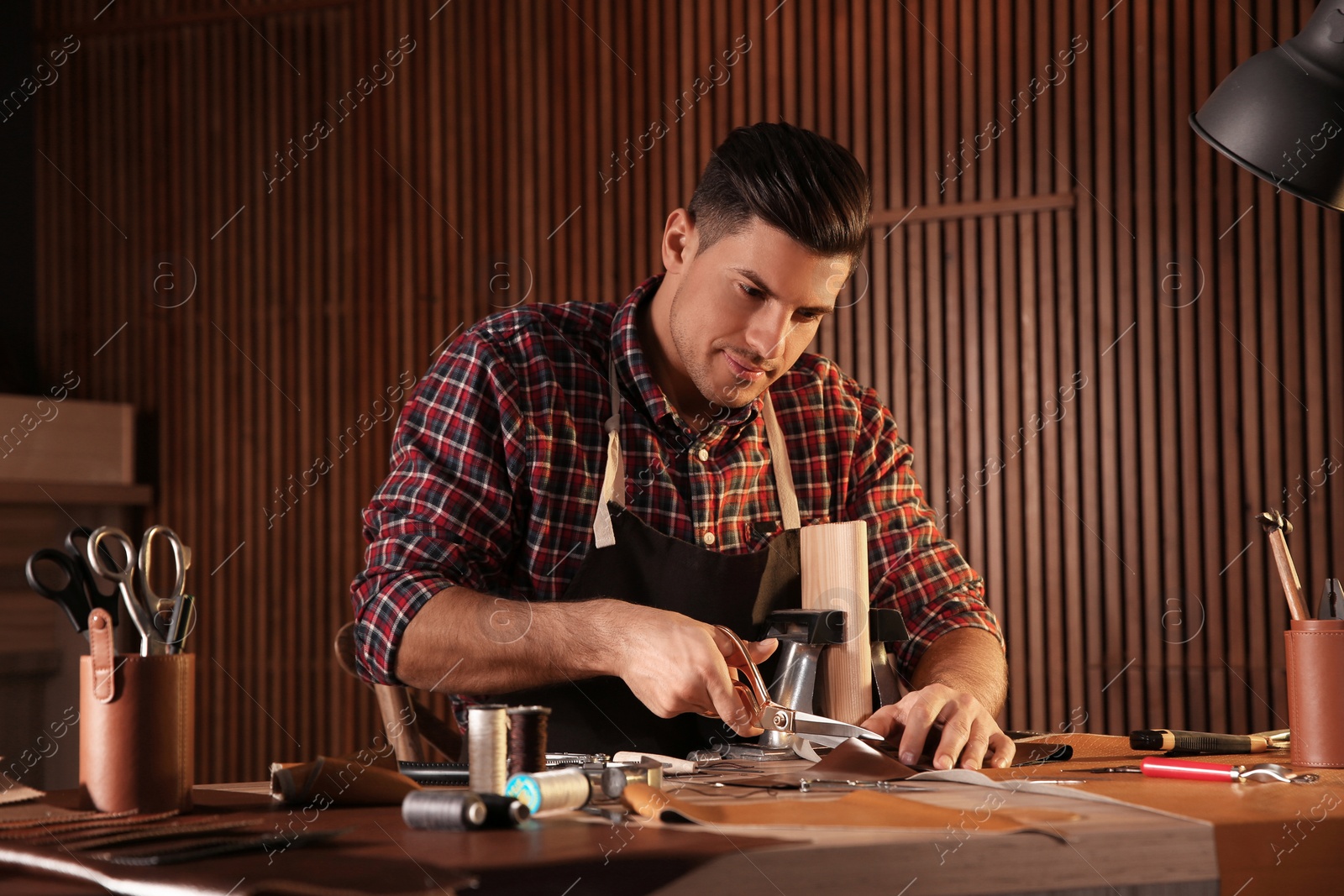 Photo of Man cutting leather with scissors in workshop