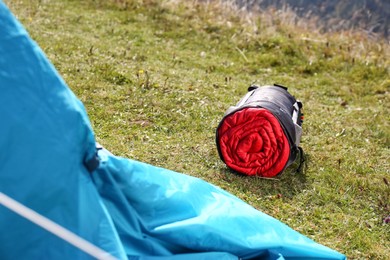 Photo of Red sleeping bag in sack on green grass outdoors