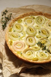 Tasty leek pie with thyme on light table, closeup