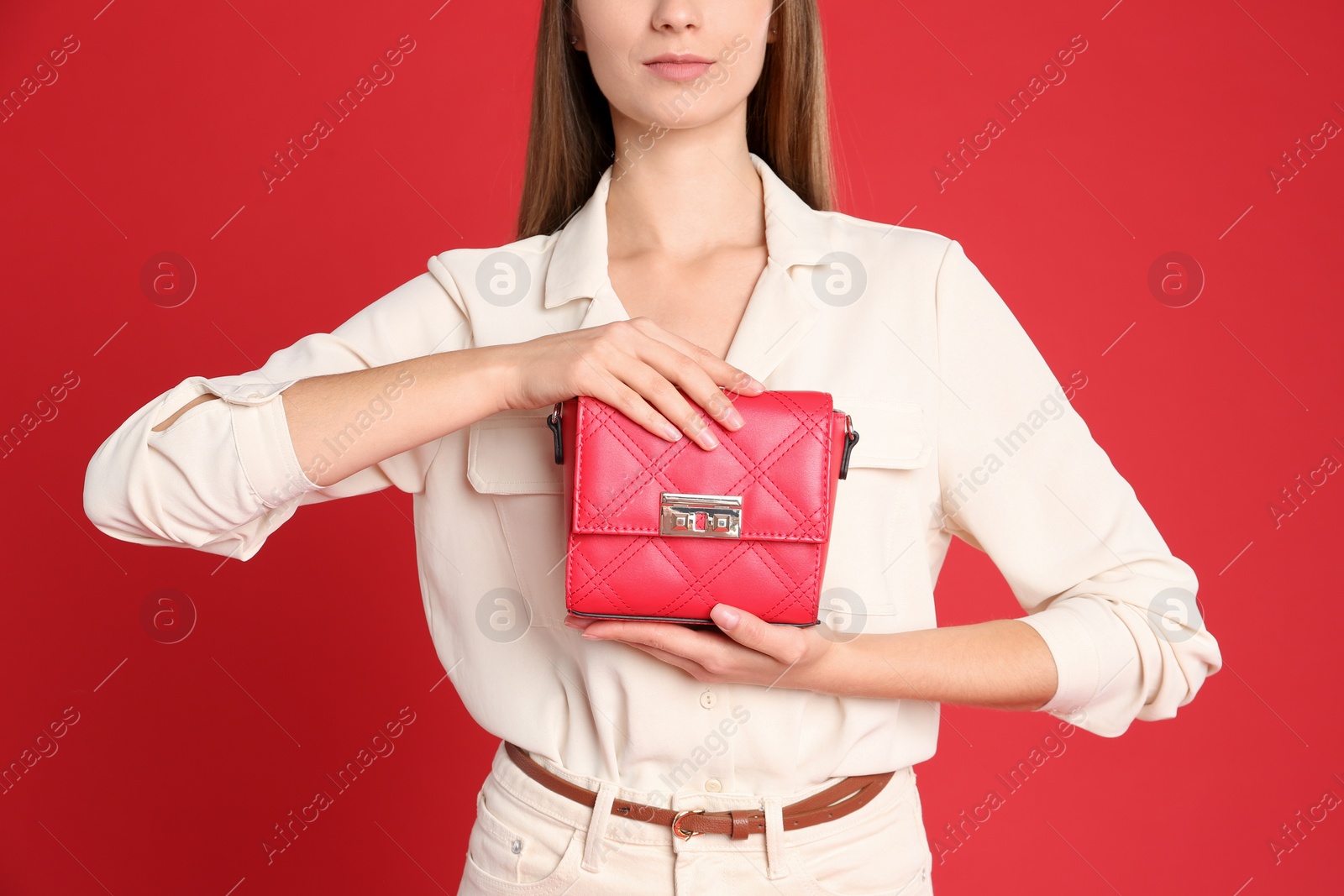 Photo of Young woman in casual outfit with stylish bag on red background, closeup