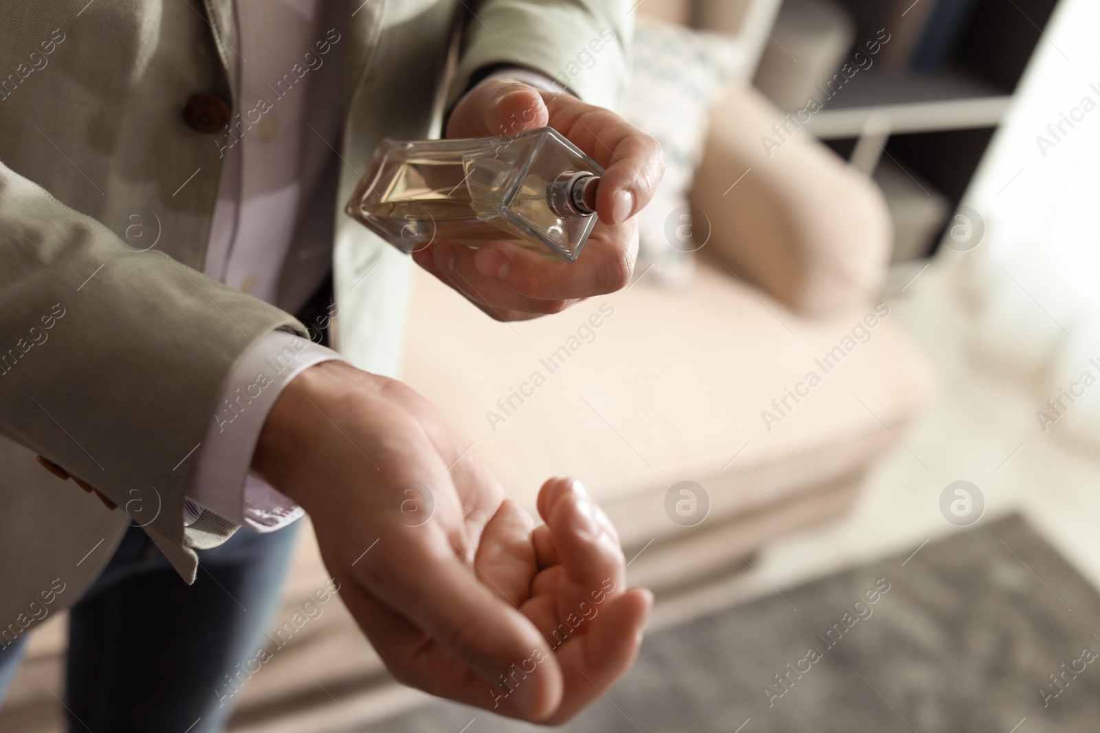 Photo of Man applying perfume on wrist indoors, closeup. Space for text