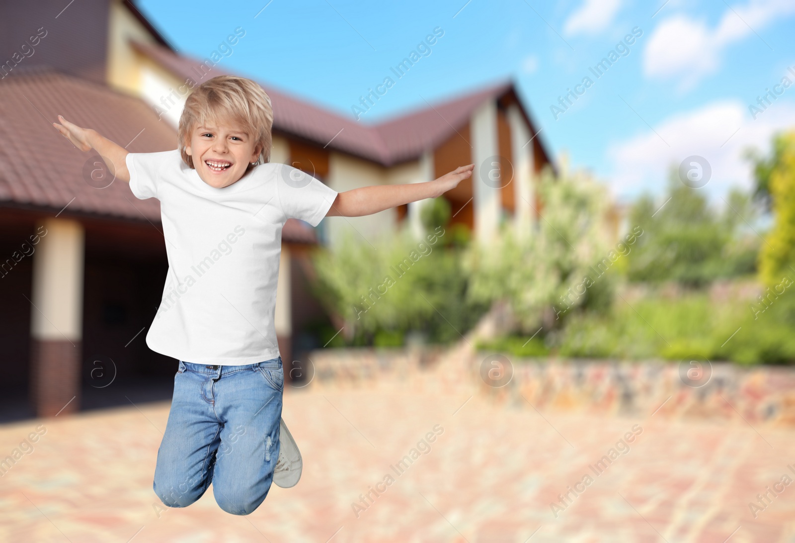 Image of Happy boy jumping near house, space for text. School holidays