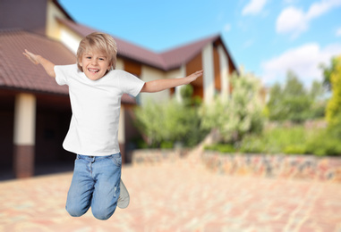 Image of Happy boy jumping near house, space for text. School holidays