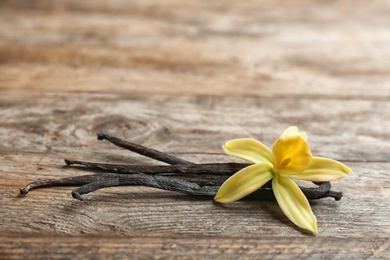 Photo of Vanilla sticks and flower on wooden background. Space for text