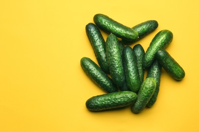 Photo of Heap of fresh ripe cucumbers on yellow background, flat lay. Space for text