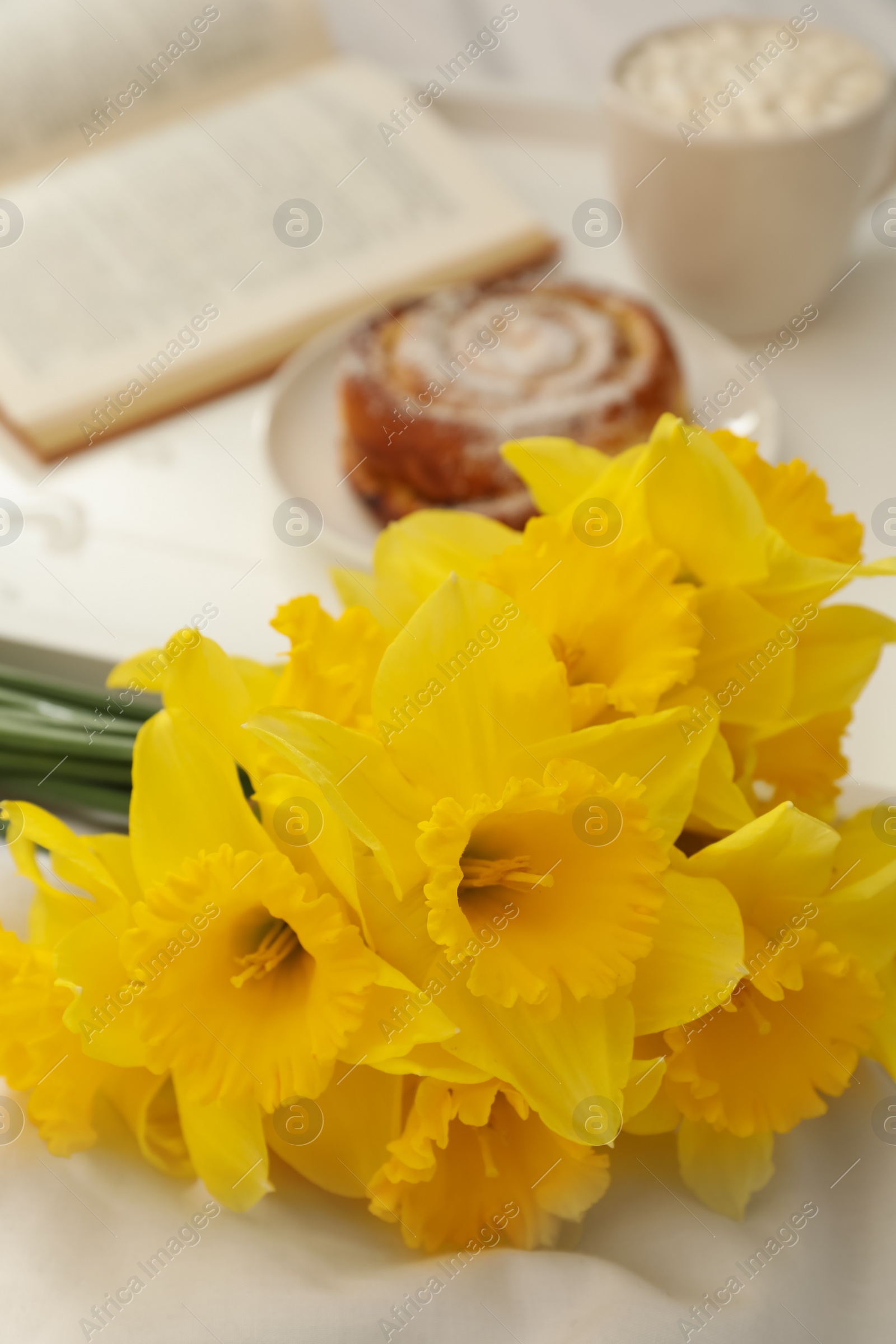 Photo of Bouquet of beautiful daffodils on white bed, closeup
