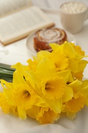 Bouquet of beautiful daffodils on white bed, closeup