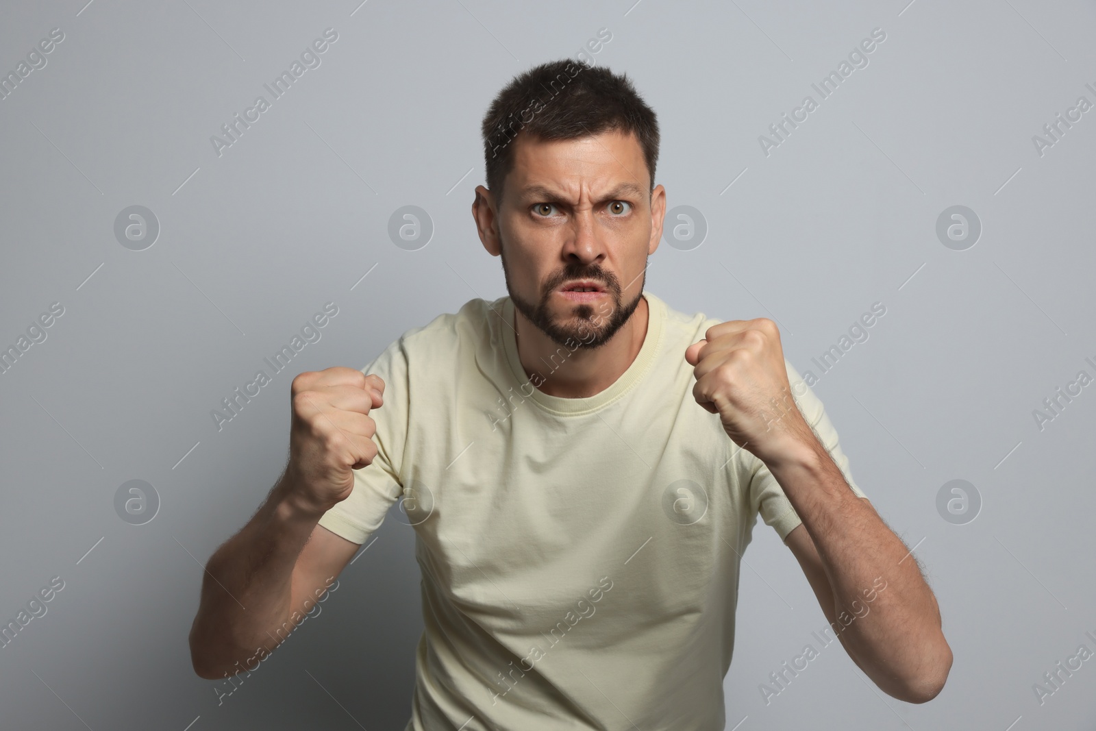 Photo of Aggressive man ready to fight on grey background