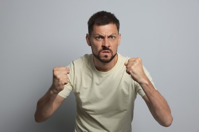 Photo of Aggressive man ready to fight on grey background