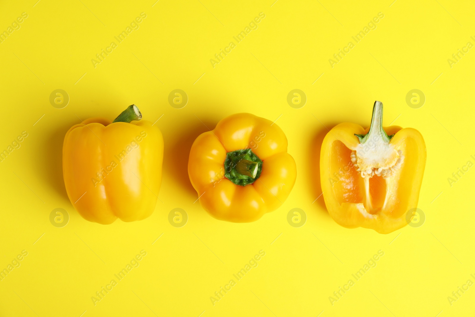 Photo of Ripe bell peppers on yellow background, flat lay