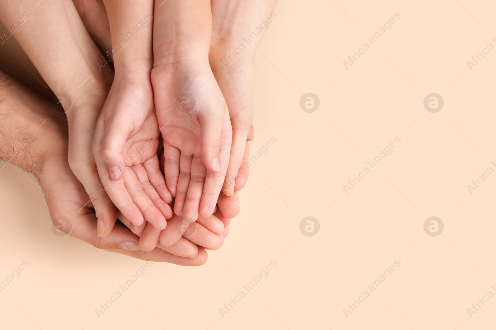 Photo of Top view of parents and kid holding empty hands together on beige background, space for text. Family day