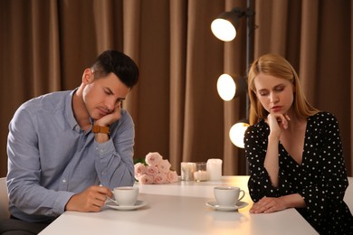 Photo of Displeased man and young woman in restaurant. Failed first date