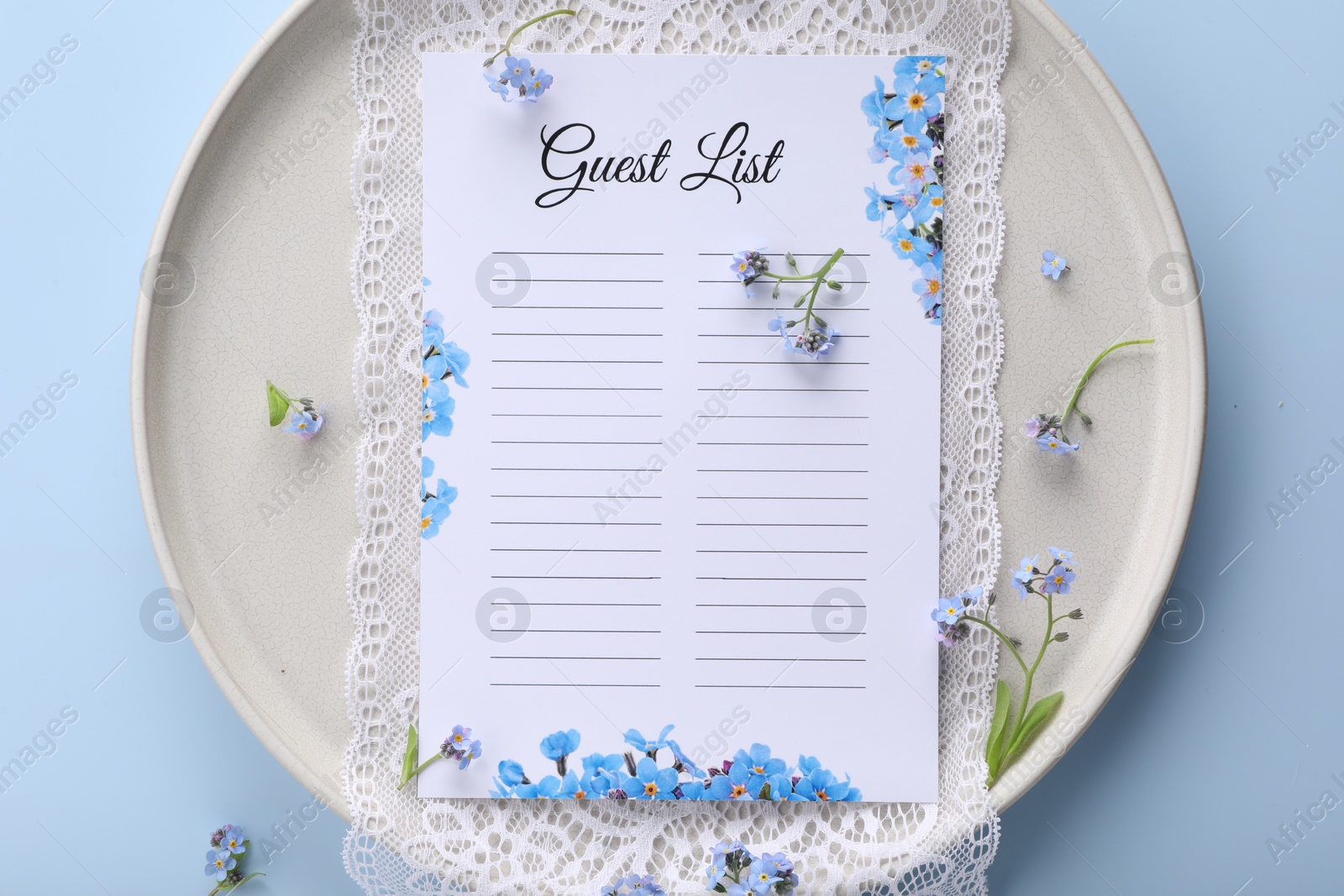 Photo of Plate with guest list, lace and flowers on light blue background, top view. Space for text