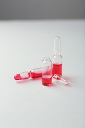 Photo of Glass ampoules with liquid on white background