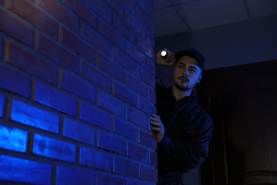 Male security guard with flashlight in dark corridor