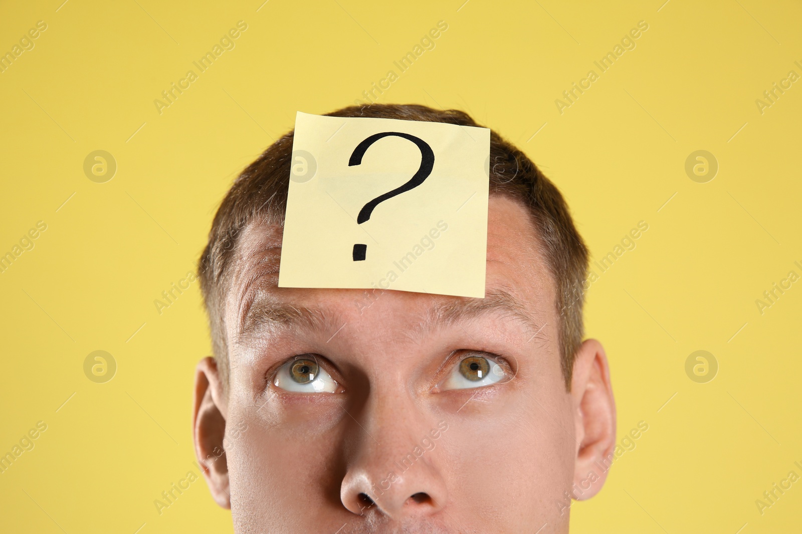 Photo of Emotional man with question mark on yellow  background, closeup