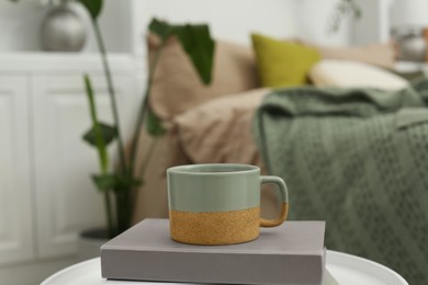 Cup and book on white table in stylish bedroom