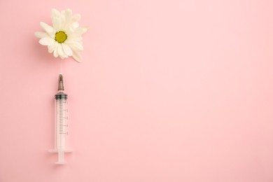 Photo of Medical syringe and beautiful chrysanthemum flower on pink background, top view. Space for text