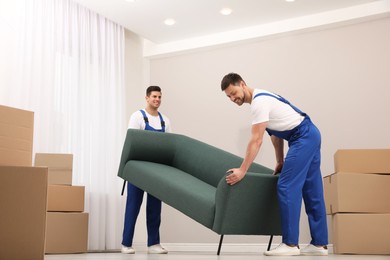 Professional movers carrying sofa in new house