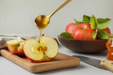Photo of Pouring sweet honey onto fresh apple on white table